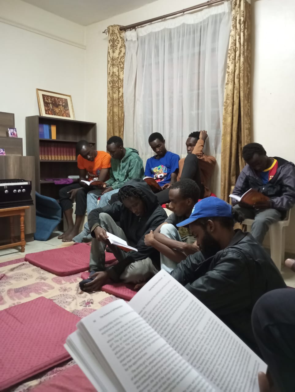 Devotees sitting together reading books during a Friday discussion at ISKCON JUJA